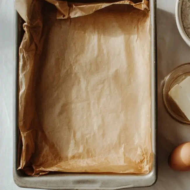 Cake pan lined with parchment paper and floured blackberries ready for baking.
