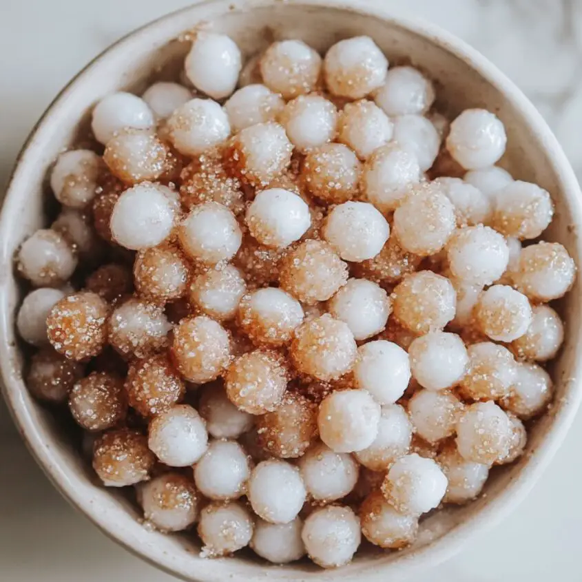 Cooked tapioca pearls coated in brown sugar on a white marble kitchen counter.