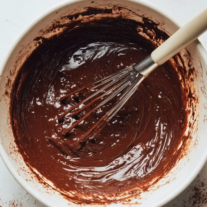 Overhead shot of glossy chocolate brownie batter in a mixing bowl
