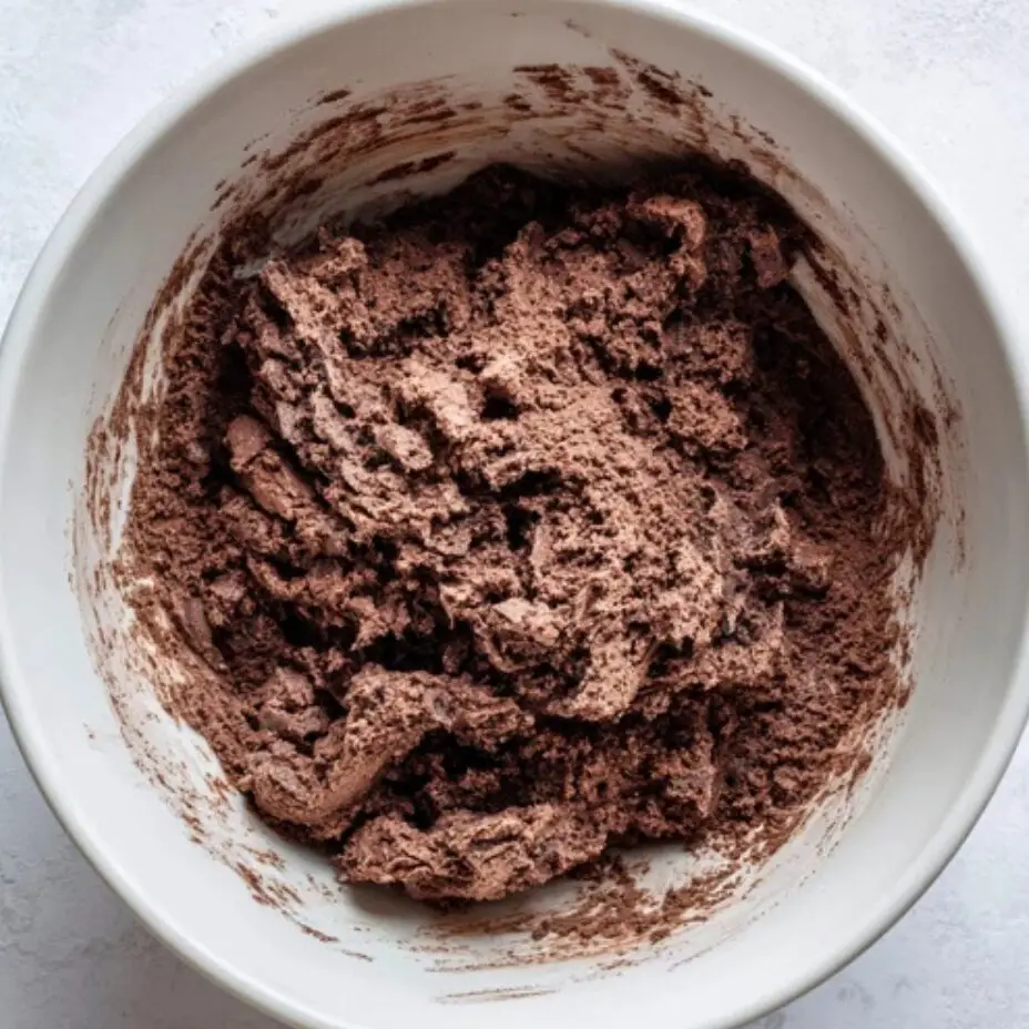 Rough homemade chocolate dough in mixing bowl on white counter