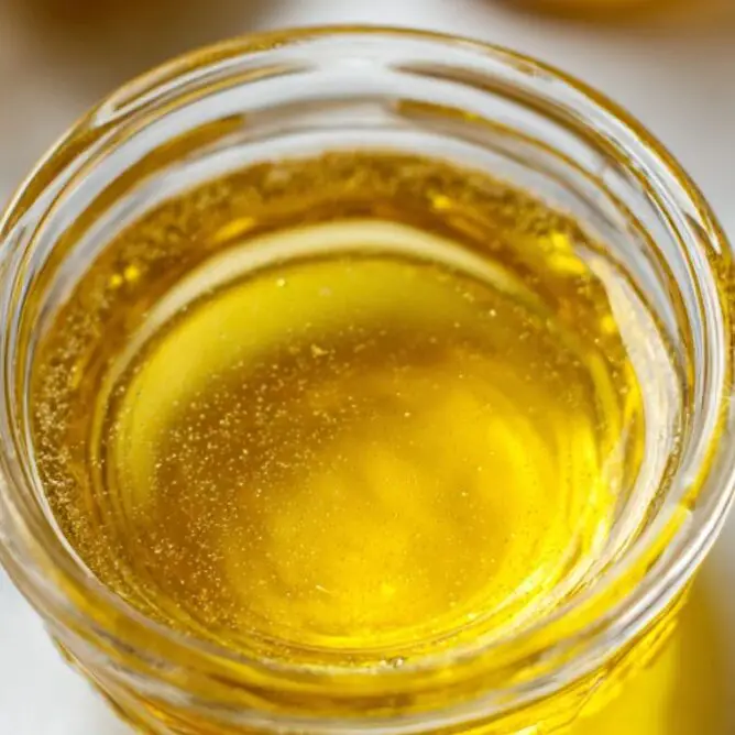 Freshly whisked lemon dressing in a glass bowl with ingredients nearby.