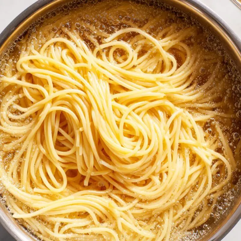 Spaghetti cooking in a pot of boiling water.