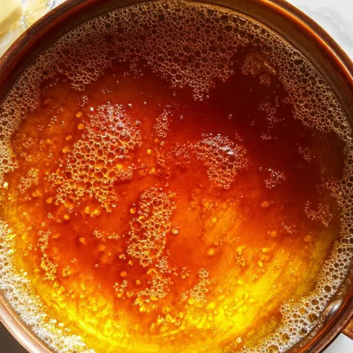 Amber caramel bubbling in a saucepan during cooking.