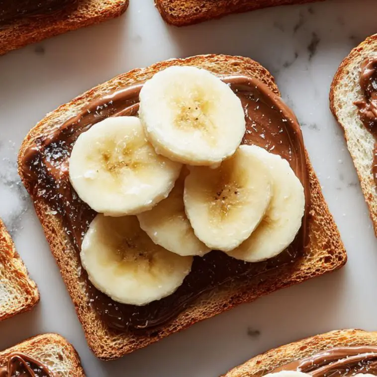 Banana slices arranged over Nutella on toast

