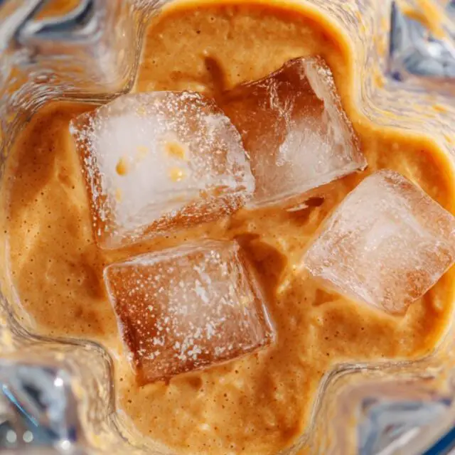 Thick caramel smoothie being blended with ice cubes