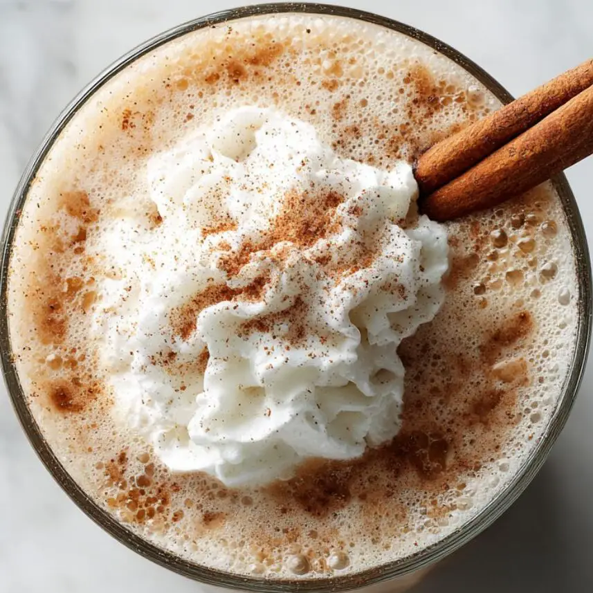 Cinnamon iced coffee topped with whipped cream and cinnamon stick garnish