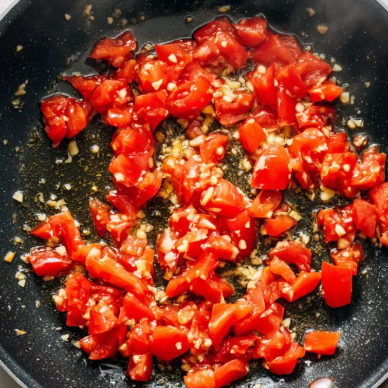 Fresh tomato sauce simmering with garlic in a skillet.