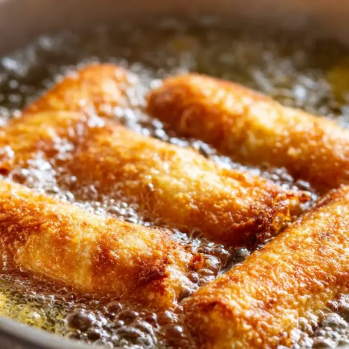 Crispy crab rolls frying in oil until golden brown.