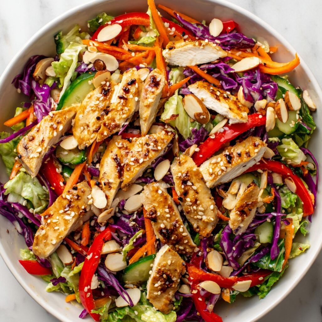 Assembled Asian sesame chicken salad with dressing and garnishes ready to serve.

