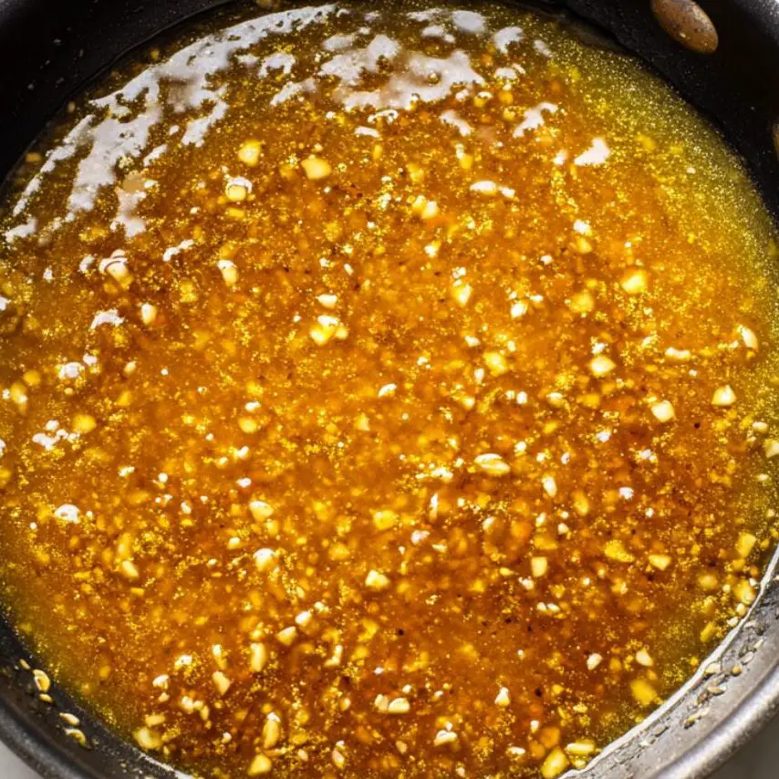 Skillet with glossy honey garlic sauce simmering.