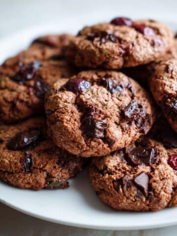 Homemade Black Forest cookies recipe with chocolate chunks and cherries on a white kitchen counter, photographed from above in a rustic, imperfect style.