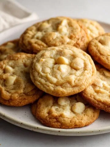 Homemade white chocolate macadamia cookies recipe on a white marble counter, overhead shot with crumbs and a rustic homemade feel.