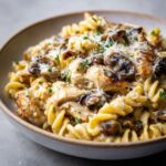 Homemade chicken marsala pasta recipe with mushrooms and creamy sauce served in a rustic bowl on a white kitchen counter, photographed from overhead.