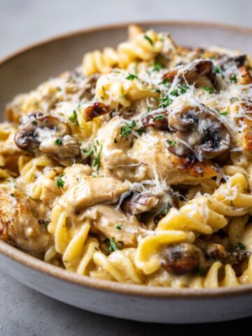 Homemade chicken marsala pasta recipe with mushrooms and creamy sauce served in a rustic bowl on a white kitchen counter, photographed from overhead.
