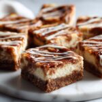 Homemade cinnamon roll cheesecake bars recipe cut into squares with glaze drizzle on a white marble counter.