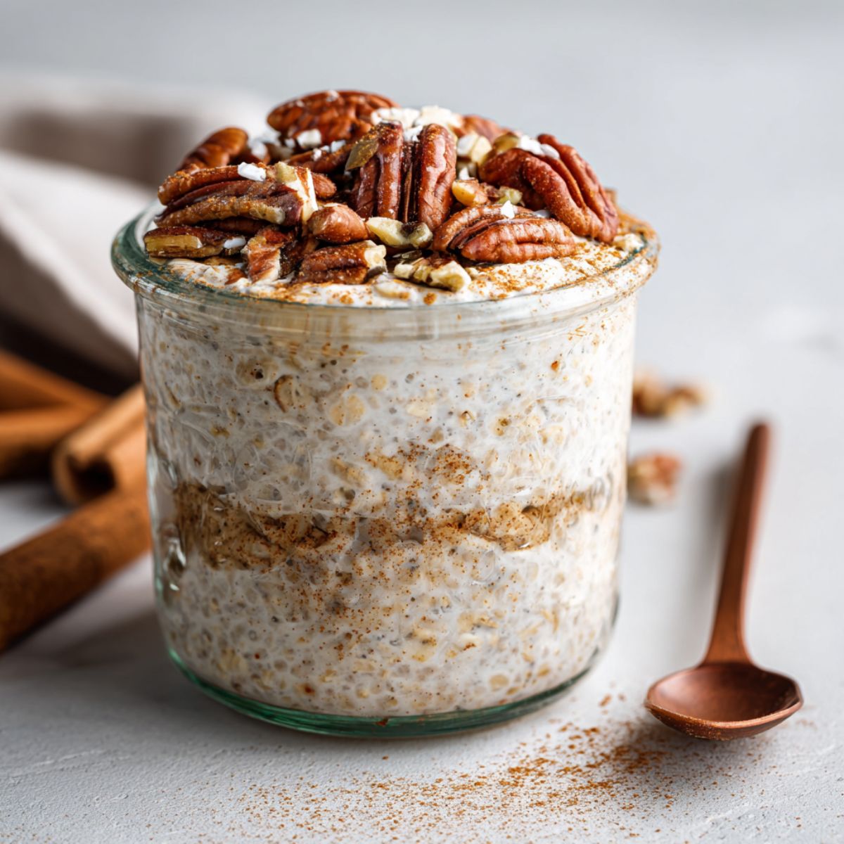Homemade gingerbread overnight oats recipe in a mason jar topped with pecans and maple syrup, photographed from above on a white kitchen counter.