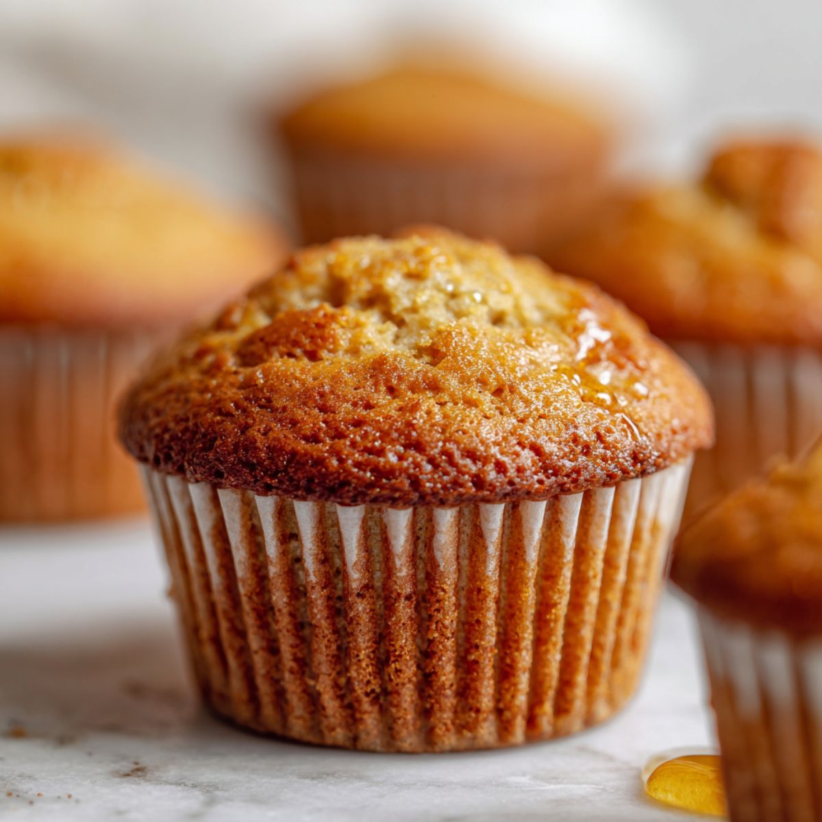 Overhead view of homemade honey cupcakes recipe on a white marble kitchen counter with a drizzle of honey, rustic and natural look.