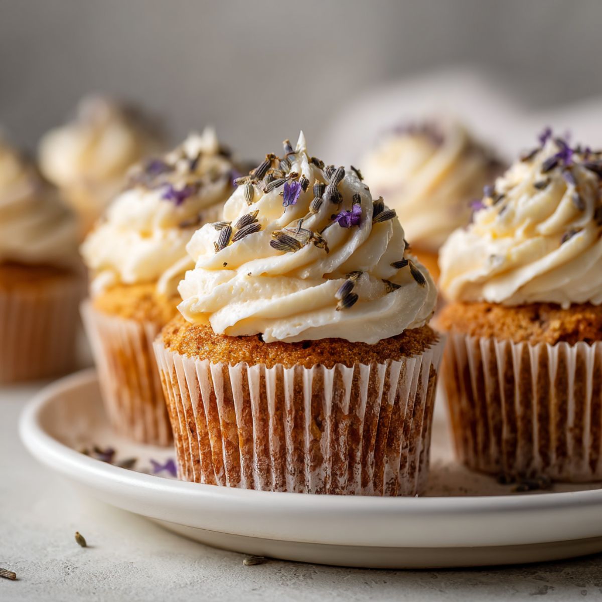 Homemade honey lavender cupcakes recipe with rustic frosting swirls and lavender buds on a white kitchen counter, shot from above.