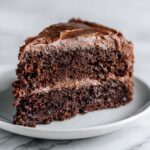 Homemade double chocolate fudge cake recipe with rich fudgy layers, sliced on a white kitchen counter.