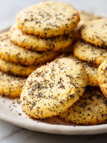 Overhead photo of homemade lemon poppy seed cookies recipe on a white marble counter, scattered with crumbs, warm and casual kitchen vibe.