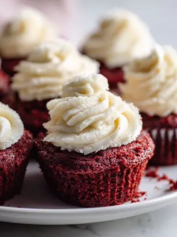 Overhead photo of homemade mini red velvet cupcakes recipe with cream cheese frosting on a white kitchen counter.