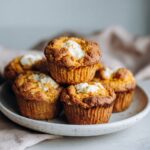 Homemade pumpkin cream cheese muffins recipe with cream cheese swirls on a white kitchen counter, overhead shot with a cozy fall feel.