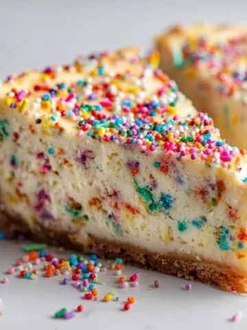 Homemade Funfetti cheesecake recipe topped with colorful sprinkles on a white kitchen counter, photographed from above in a natural homemade style.