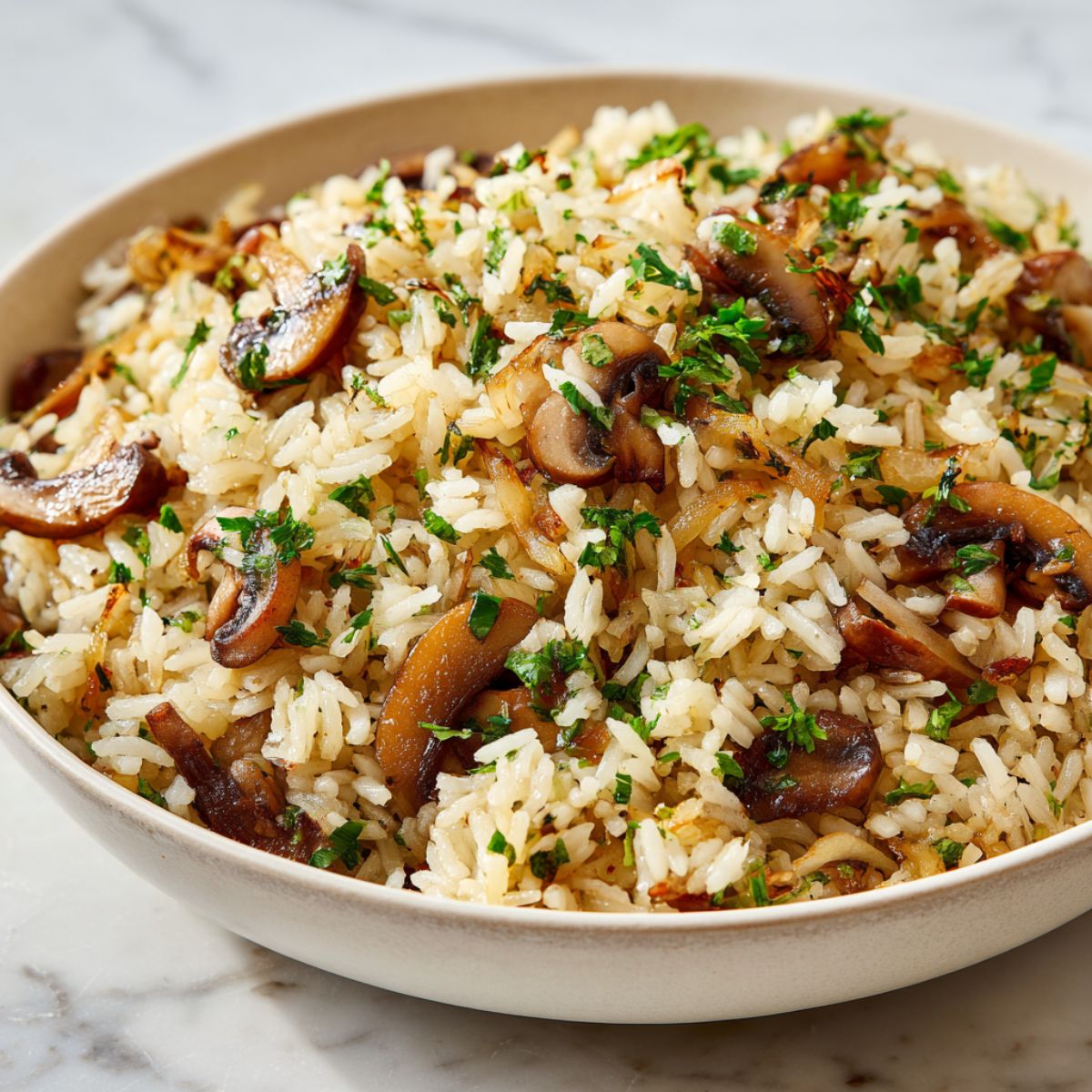 Overhead view of homemade mushroom rice pilaf recipe with mushrooms and fresh parsley on a white kitchen counter.