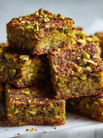 Homemade pistachio bars recipe cut into rustic squares on parchment paper, shot from above on a white kitchen counter.