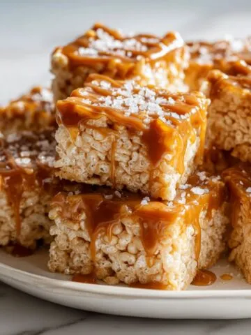 Homemade salted caramel Rice Krispie Treats Recipe cut into squares with caramel drizzle and sea salt on a white kitchen counter.