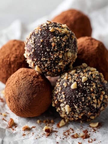 Homemade hazelnut chocolate truffles recipe dusted with cocoa and chopped hazelnuts on a white kitchen counter, photographed from above with a rustic homemade look.