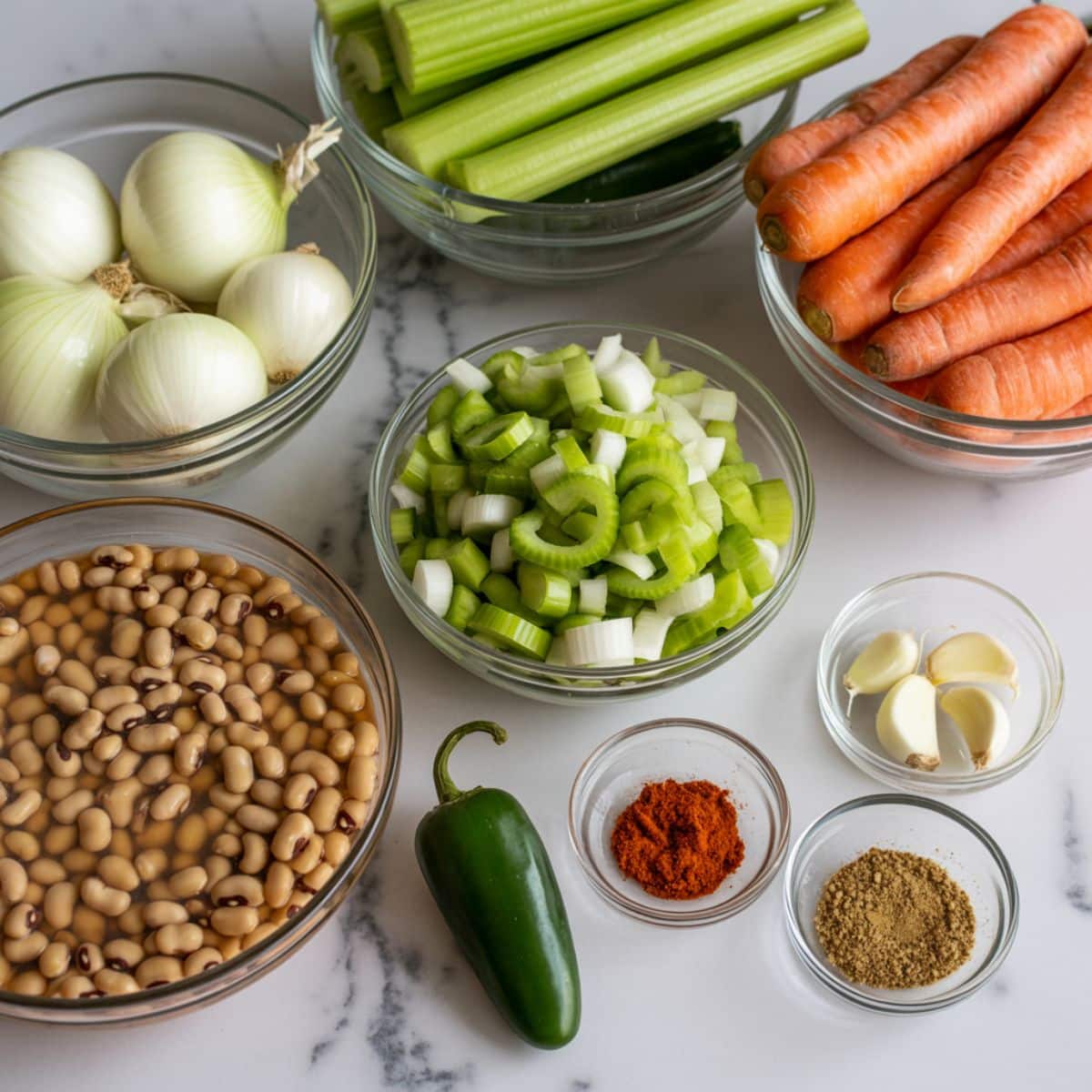 Raw ingredients for spicy black eyed pea soup, including black eyed peas, vegetables, and spices on a white kitchen counter, captured from above in a natural homemade style.