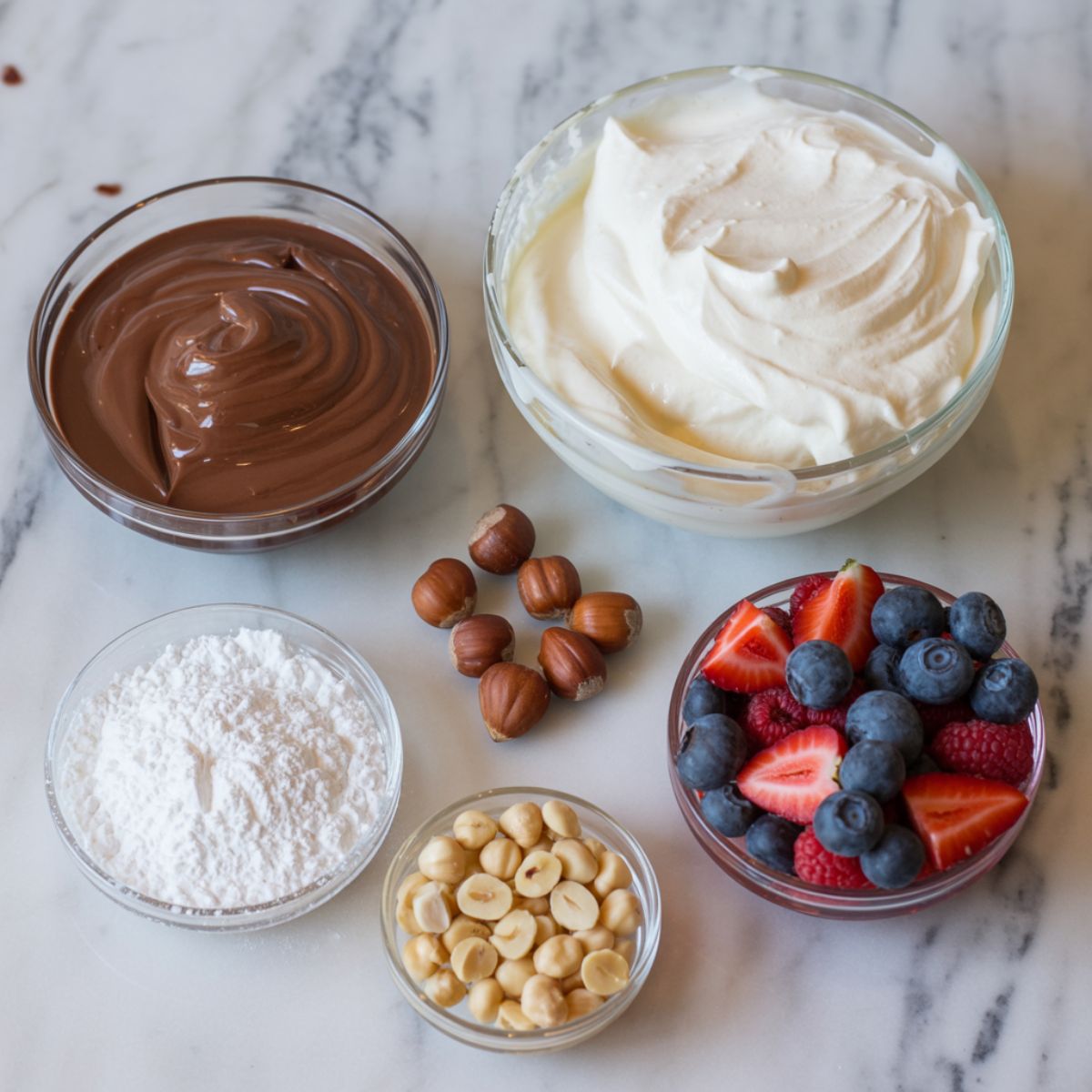 Nutella mousse ingredients — Nutella jar, heavy cream, powdered sugar, and garnishes — laid out on a white kitchen counter, photographed from above.