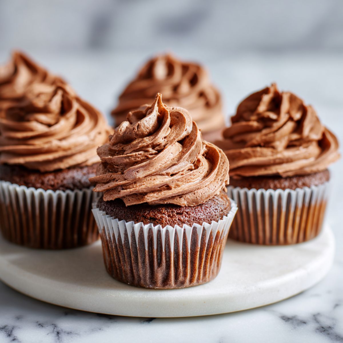 Overhead view of homemade Nutella cupcakes recipe with swirled frosting on a white kitchen counter.