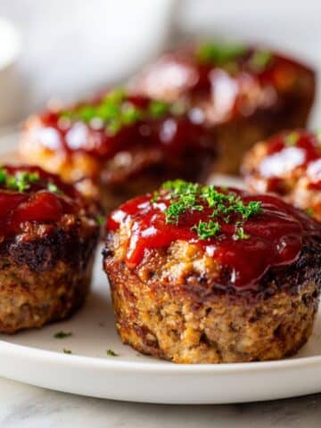 Overhead view of freshly baked homemade meatloaf cups recipe on a white marble kitchen counter with a glossy ketchup glaze, looking rustic and comforting.