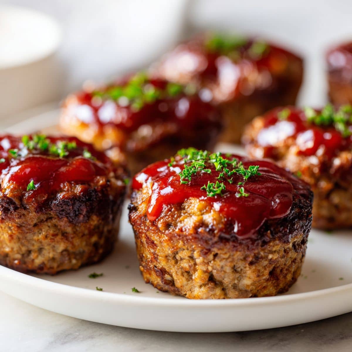 Overhead view of freshly baked homemade meatloaf cups recipe on a white marble kitchen counter with a glossy ketchup glaze, looking rustic and comforting.