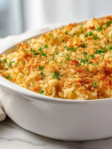 Overhead shot of a freshly baked creamy tuna noodle casserole recipe with golden cheese and breadcrumb topping on a white kitchen counter, looking homemade and cozy.