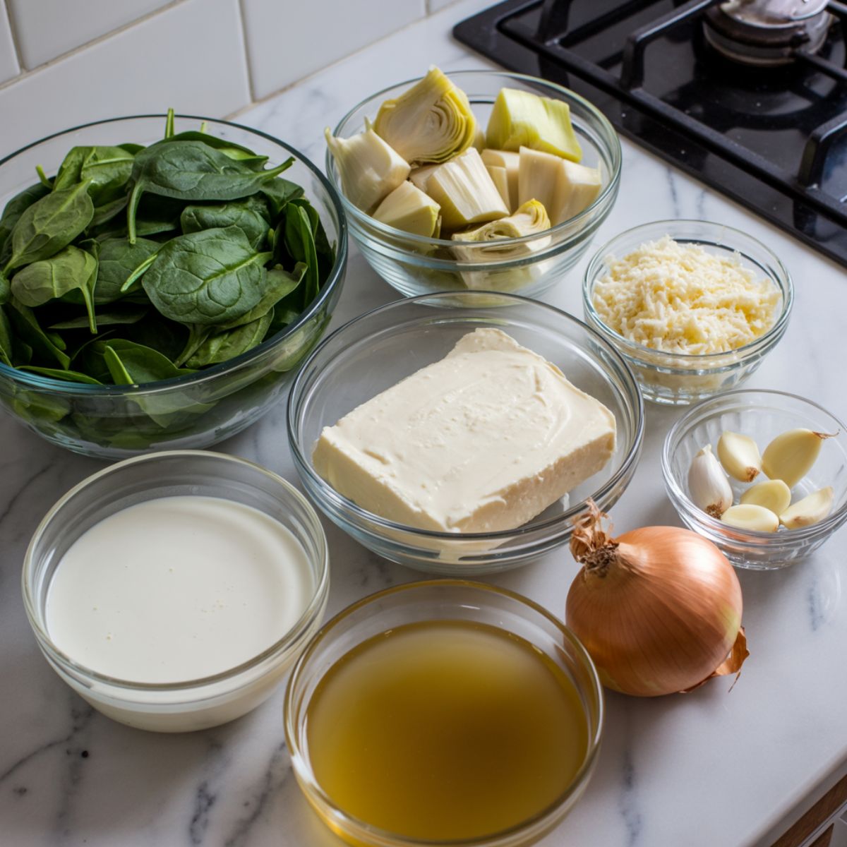 Fresh ingredients for spinach artichoke soup — spinach, artichokes, cream cheese, parmesan, garlic, and onion — arranged casually on a white marble counter from an overhead view.