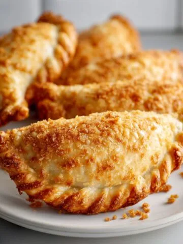 Overhead shot of homemade tuna empanadas recipe with golden flaky crust and savory tuna filling on a white kitchen counter, photographed in natural light for a real homemade look.