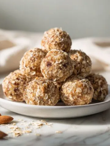 Homemade almond energy balls recipe on a white marble kitchen counter with scattered oats and almonds, captured from an overhead angle in natural light.