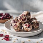 Overhead photo of homemade cranberry energy balls recipe on a white marble counter with scattered oats and cranberries, looking rustic and real.