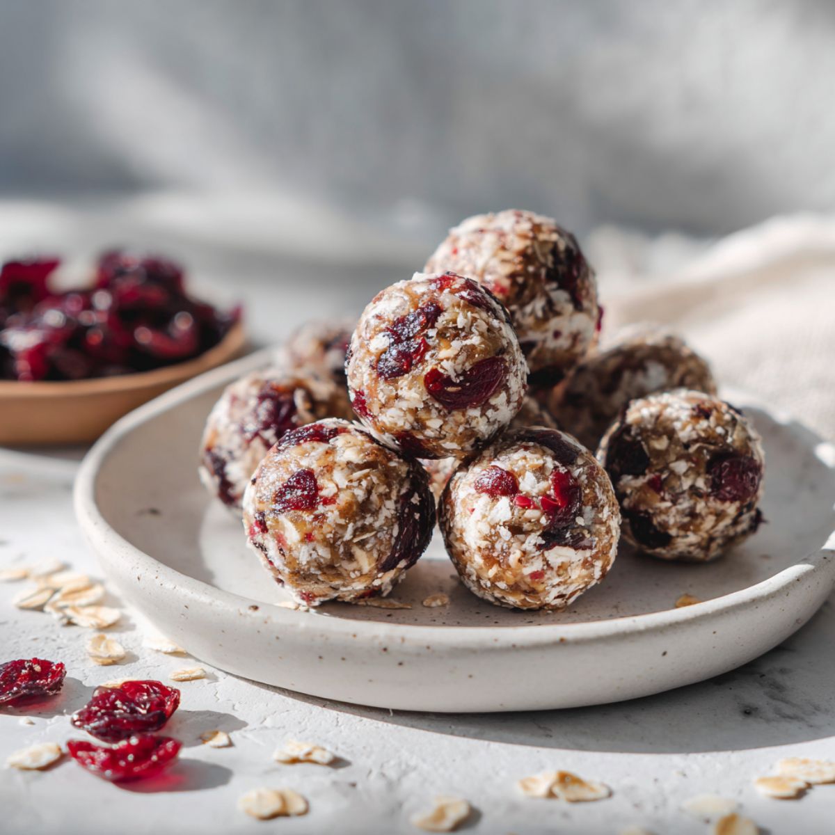 Overhead photo of homemade cranberry energy balls recipe on a white marble counter with scattered oats and cranberries, looking rustic and real.